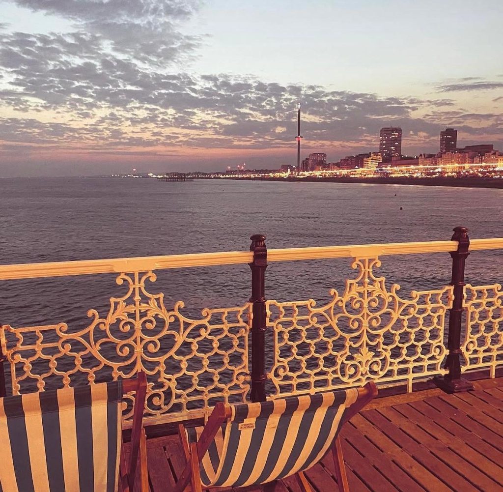 Deckchairs on Brighton Pier with sunset - Wedded Escapes - Honeymoon & Mini-moon Inspo